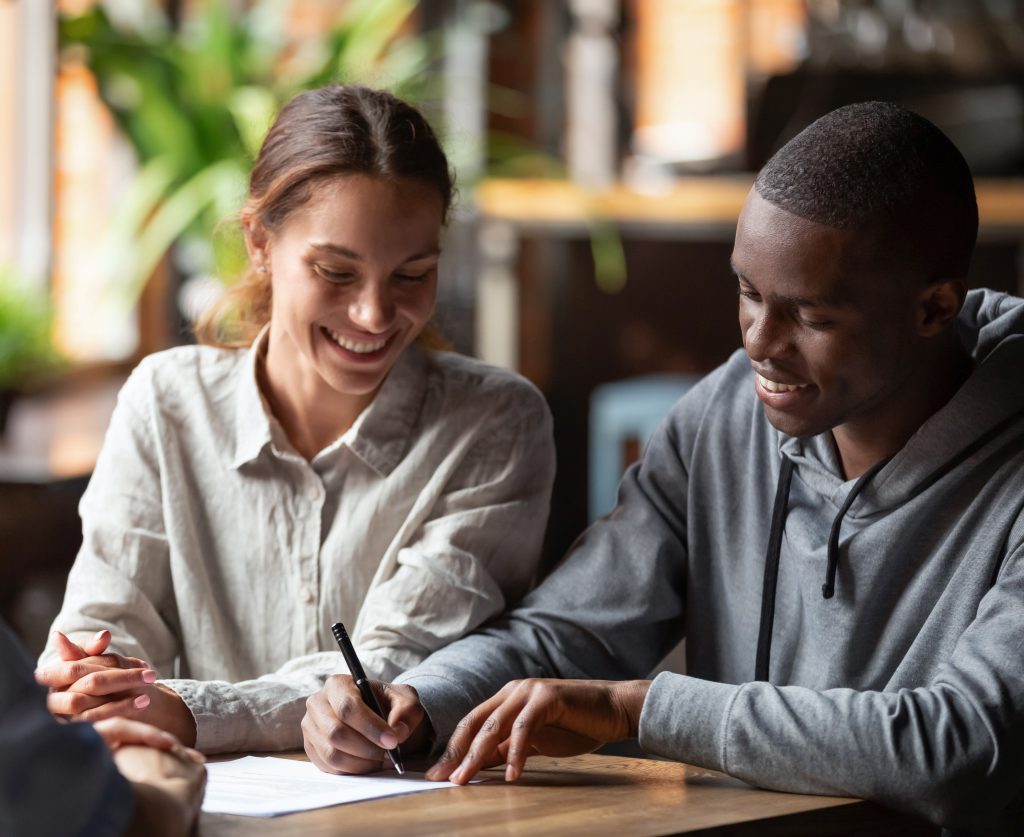 Happy mixed ethnicity couple customers sign mortgage loan contract